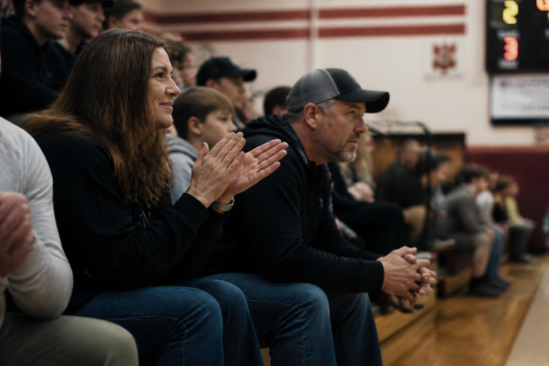 Sports parents watching their athlete from the bleachers at a youth basketball game